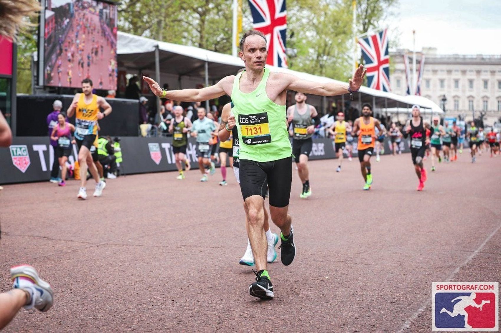 John crossing a marathon finish line with both arms outstretched